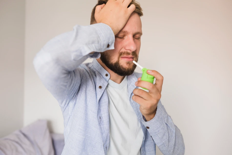 Man using spray for sore throat